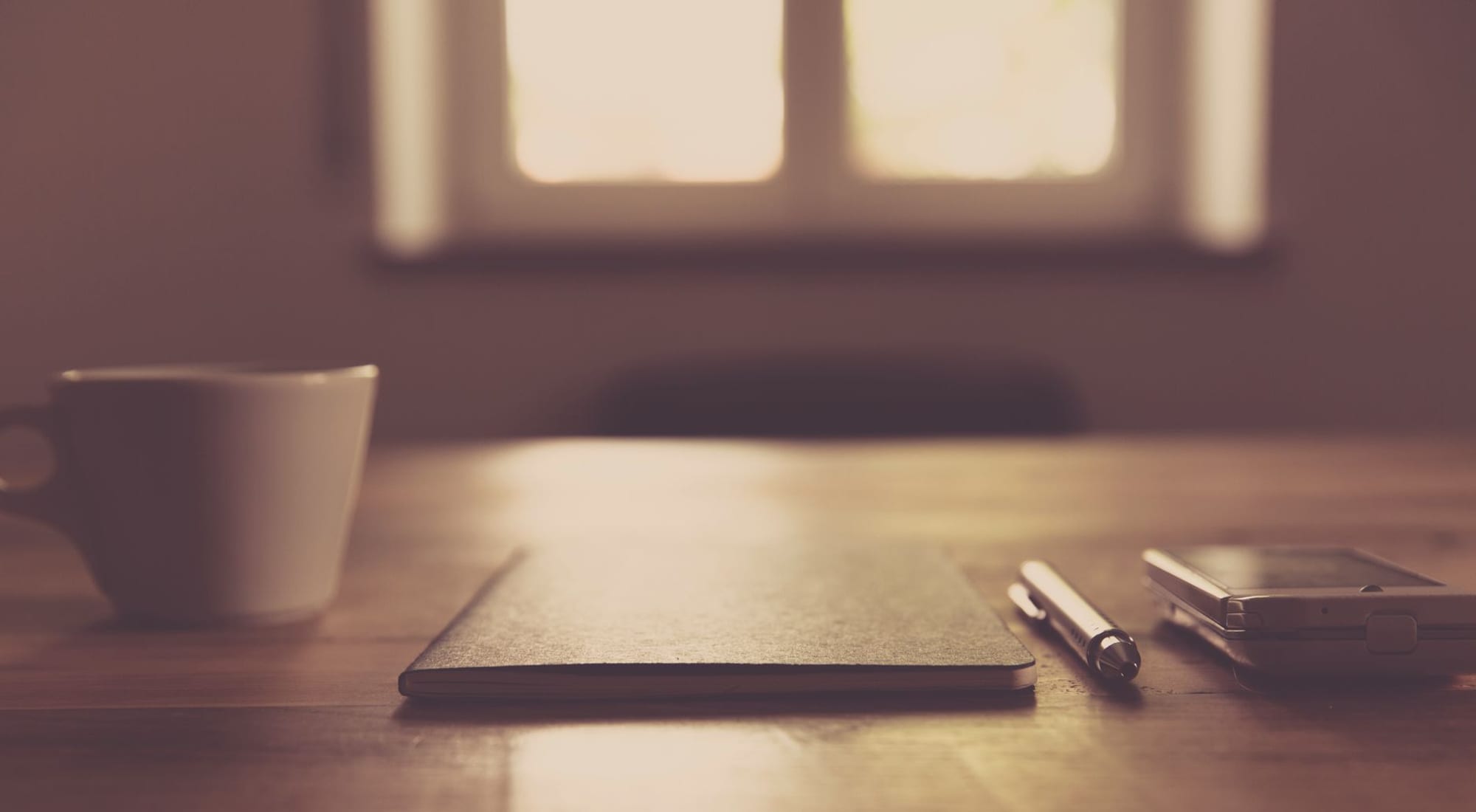 Soft natural daylight falling across a quiet wooden desk — a calm, unhurried scene.